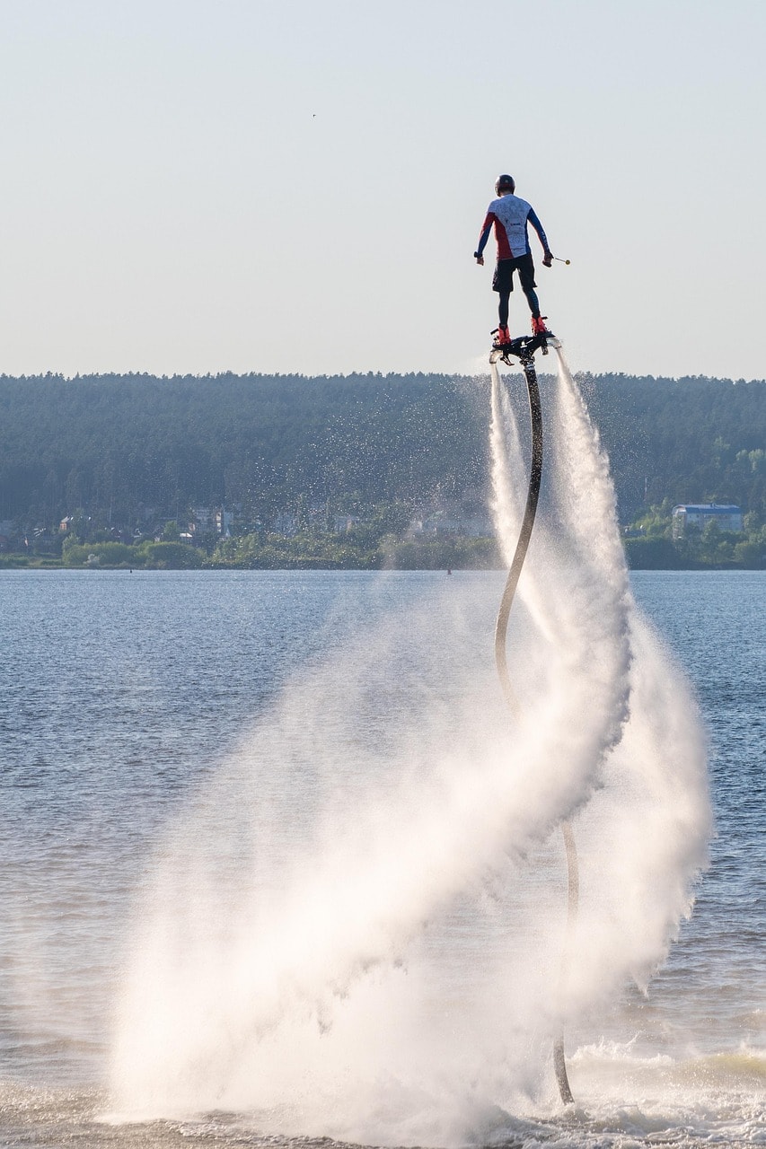 Flyboard rider rising high above open water on twin water jets